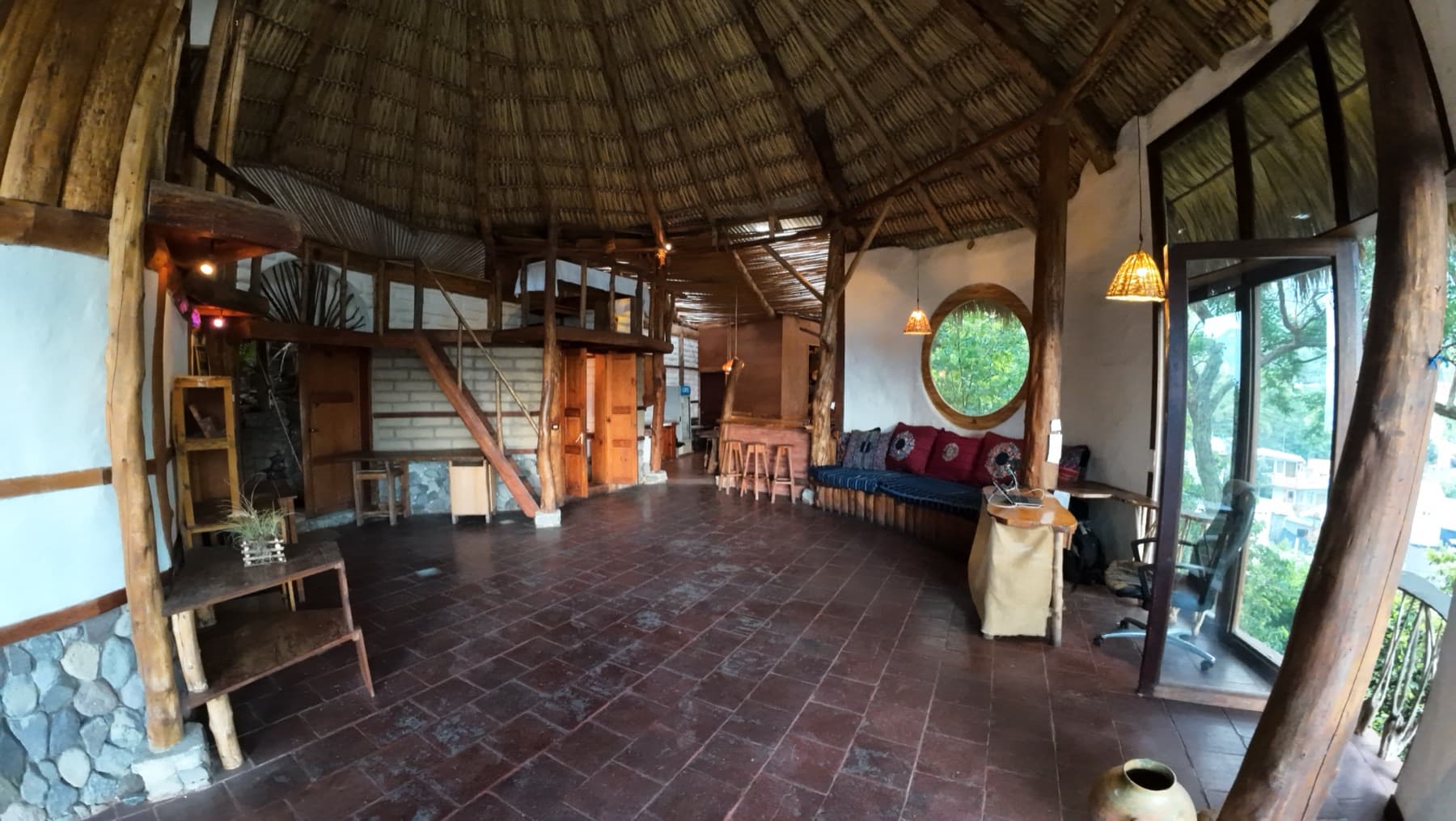 The open main floor at El Taller, with a mezzanine loft, bar, and round window